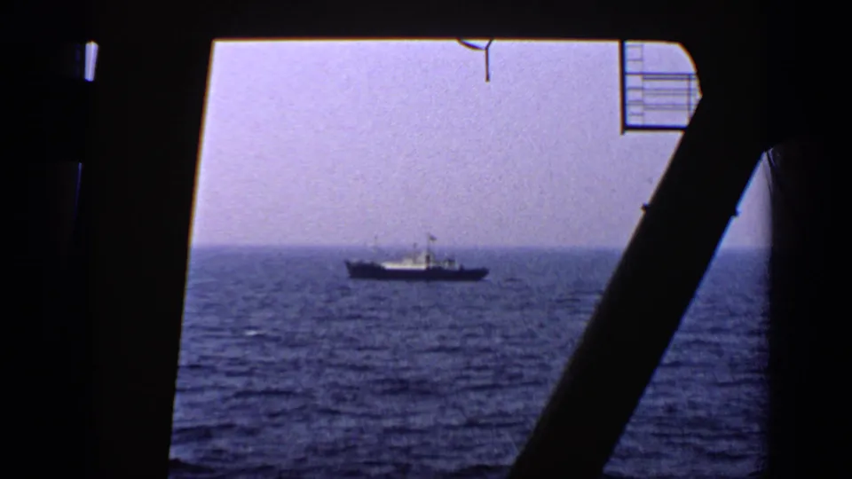 The final 1970 United Kingdom 8mm frame shows a distant ship at sea behind bold silhouetted foreground beams.