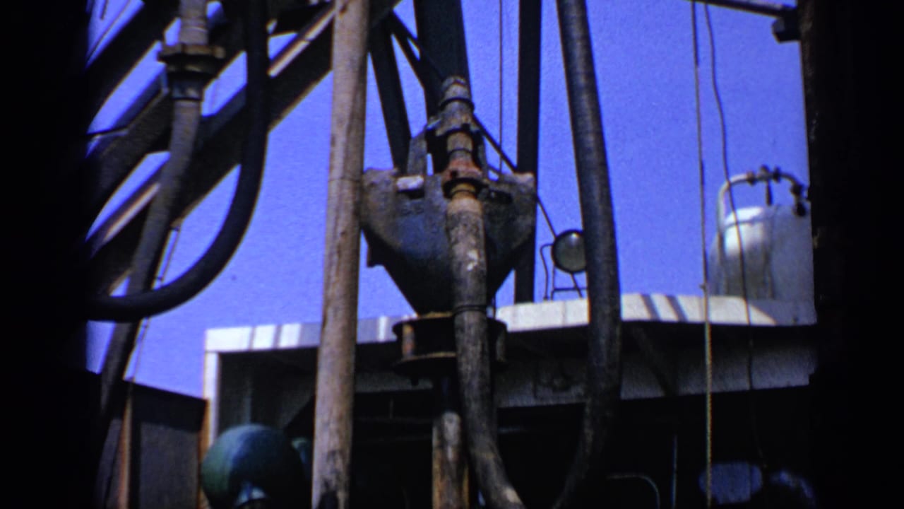 Oil-rig pipework and hoses framed close beside metal structure.