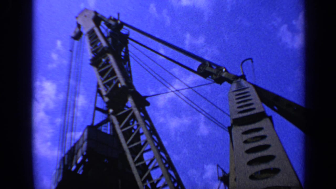 Low-angle view of a crane boom and cables against a deep blue sky.