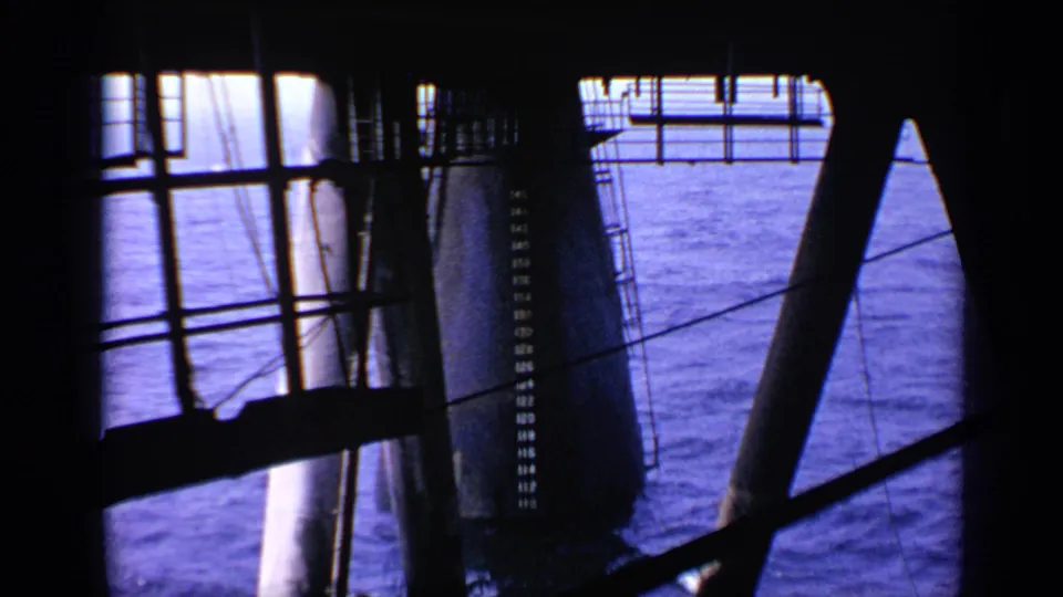 1970 United Kingdom 8mm view from inside an offshore platform, with sea visible between railings and steel support legs.