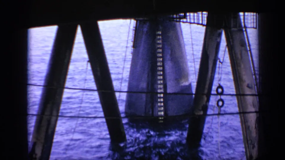 1970 United Kingdom 8mm frame showing massive oil-rig supports descending toward churning water below.