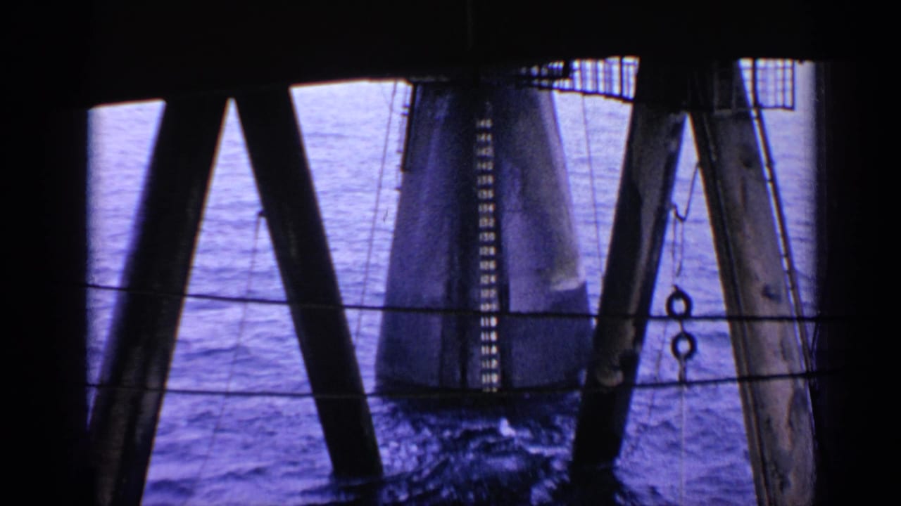 Dark coastal structure framing water and a large cylindrical pylon.