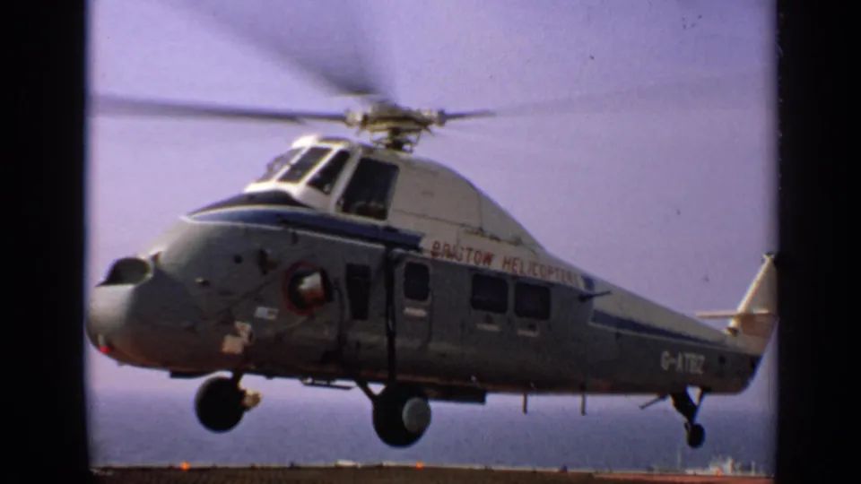 1970 United Kingdom 8mm frame of a Bristol Helicopters aircraft in flight, with spinning rotor and visible side markings.