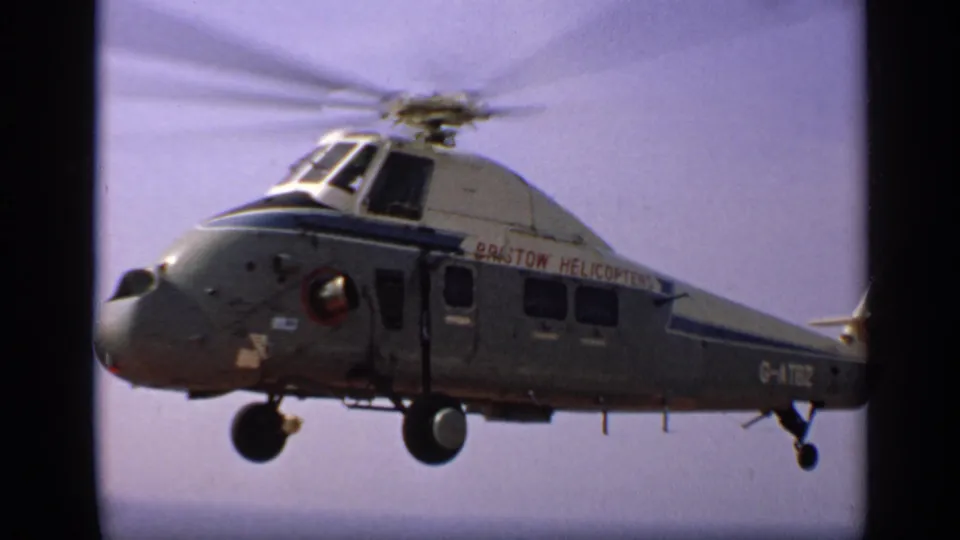 1970 United Kingdom frame showing a Bristol Helicopters aircraft with registration G-ATBZ, rotor blur, and landing gear visible.