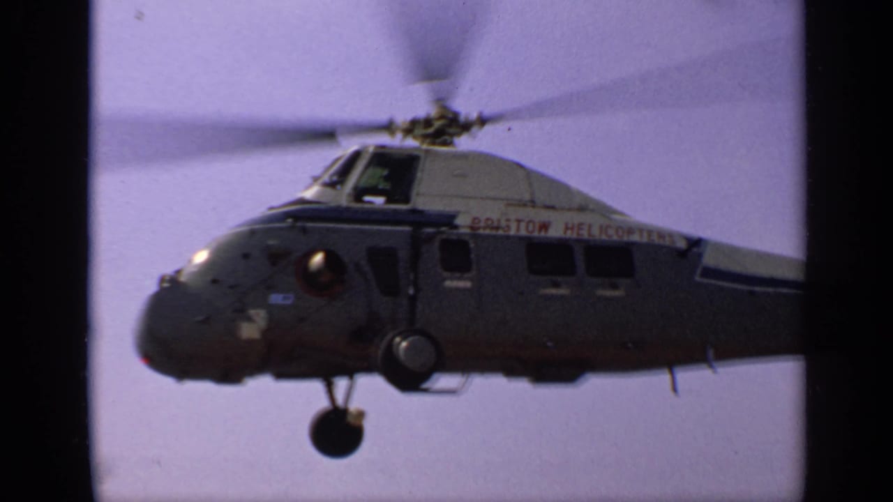 Side view of a helicopter in flight with red lettering on the fuselage.