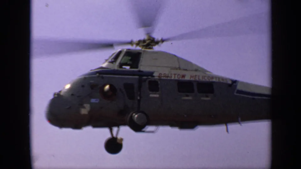 1970 United Kingdom frame of the marked helicopter moving through the sky, with side windows and landing gear visible.