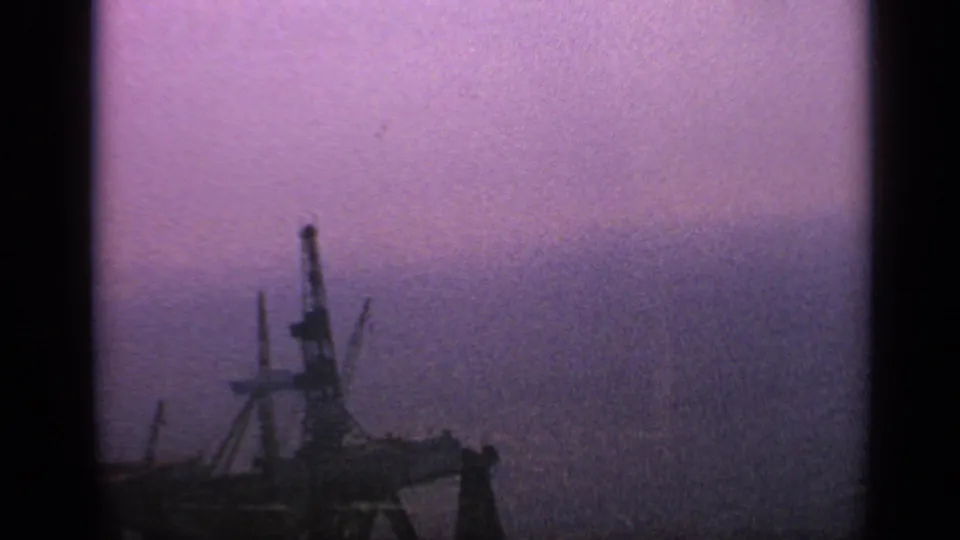 1970 United Kingdom 8mm frame showing the offshore structure partly low in frame beneath grainy purple haze.