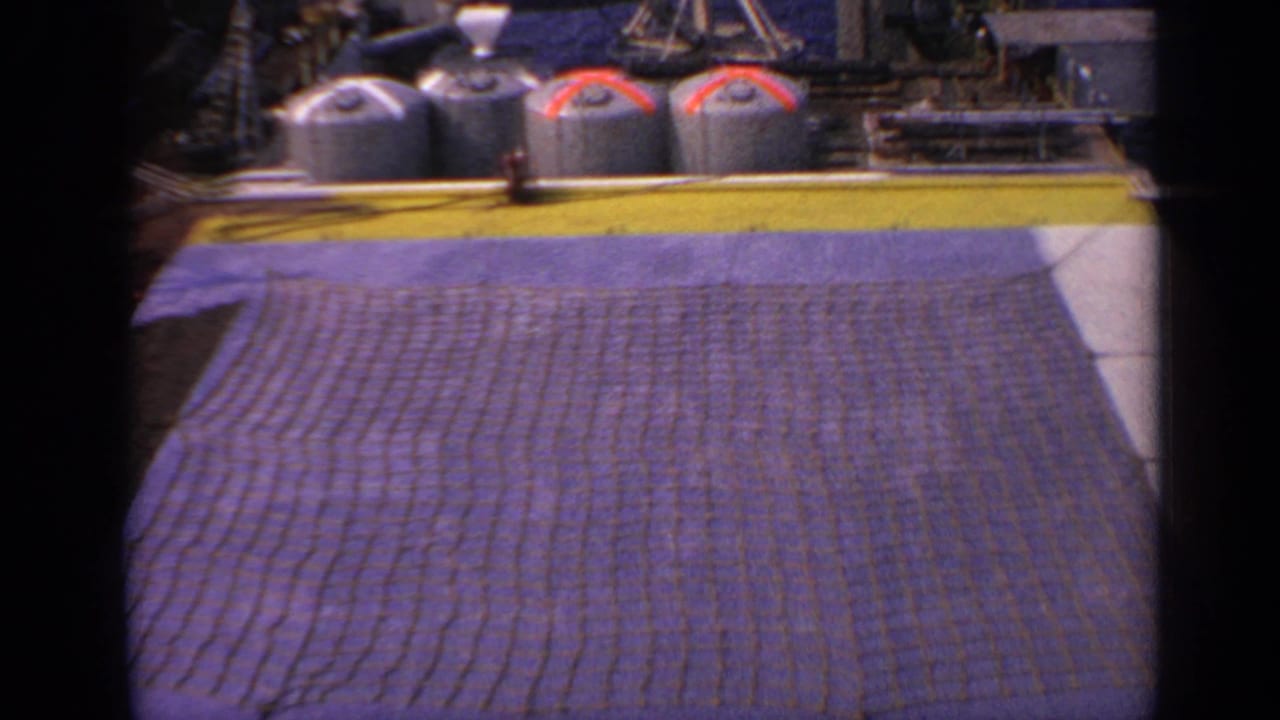 Industrial deck with brown net or mat, tanks and yellow edge.