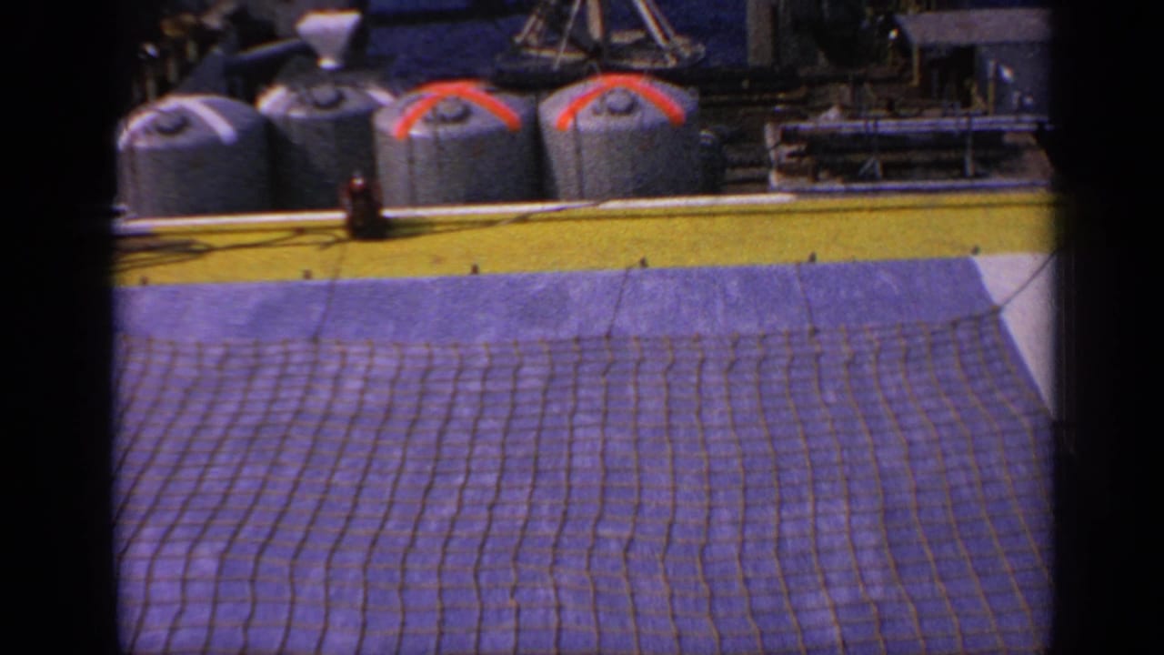 Similar platform deck view with tanks, netting, and dark frame edge from the film scan.