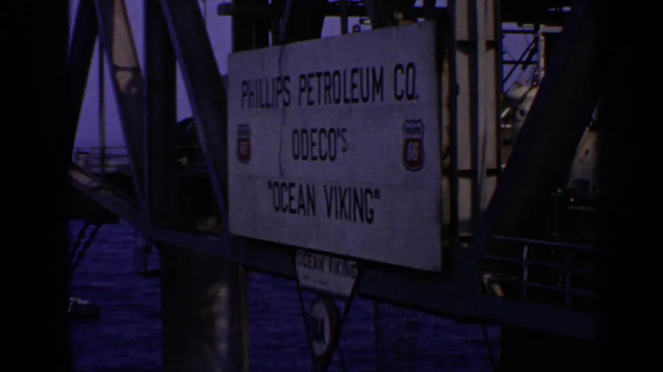 A sign on a rig structure identifies Phillips Petroleum Co. and Odeco's Ocean Viking, with beams and deck shadows around it.