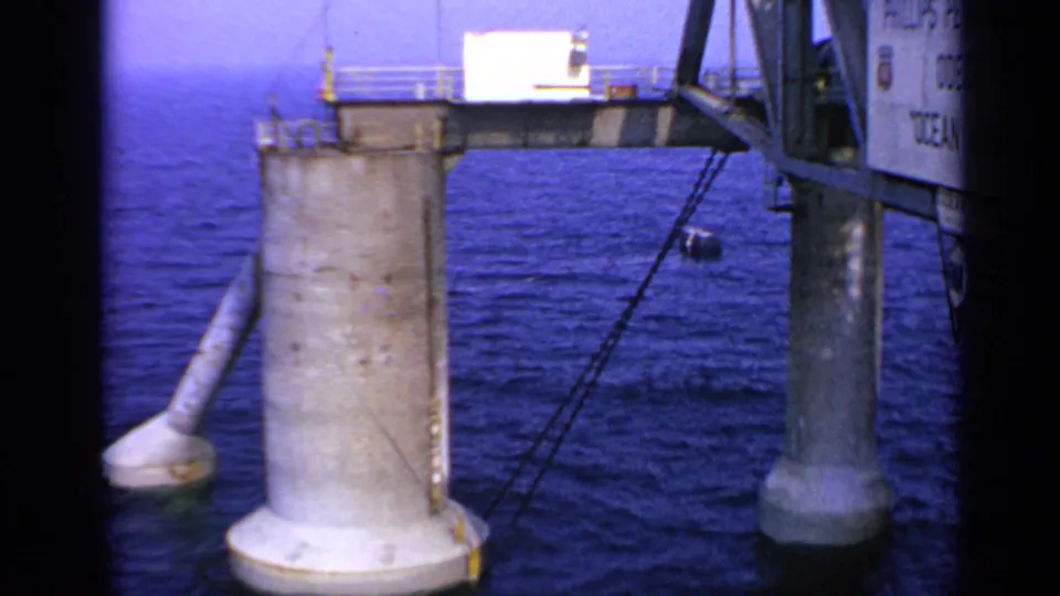 1970 United Kingdom 8mm view of offshore platform legs, a partial Ocean Viking sign, cables, and surrounding blue sea.