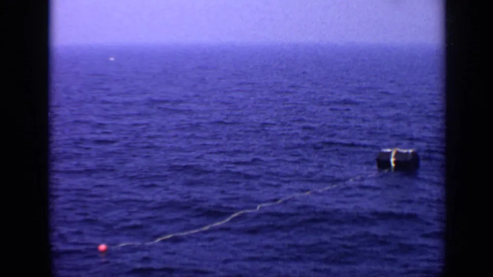 1970 8mm ocean shot showing a buoy system spread across the water under a pale horizon.