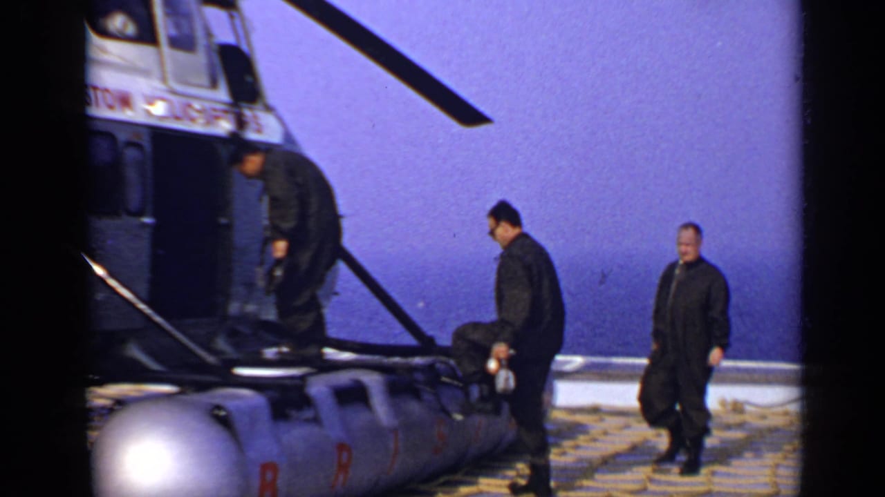 Three men in dark clothing beside a Bristol Helicopters aircraft on a sunny day.