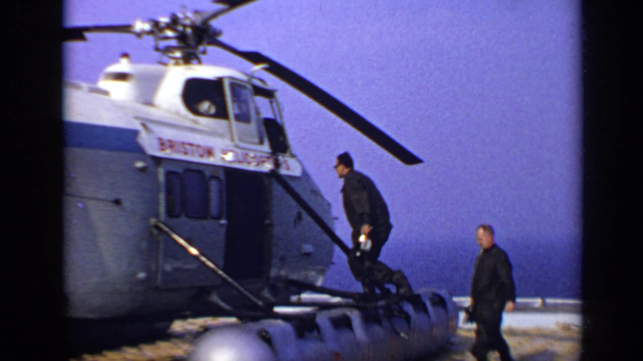 Two men board a helicopter while another stands near the open door.