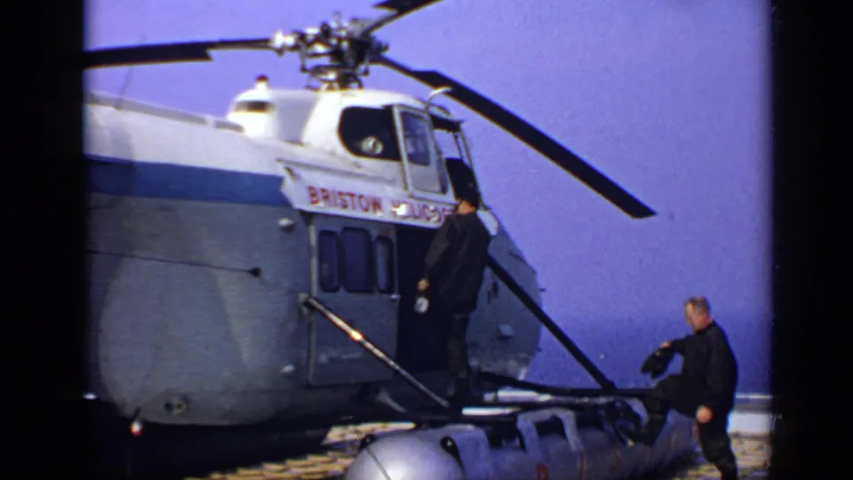 1970 United Kingdom 8mm frame with a man at the Bristol Helicopters door and another man moving across the deck.