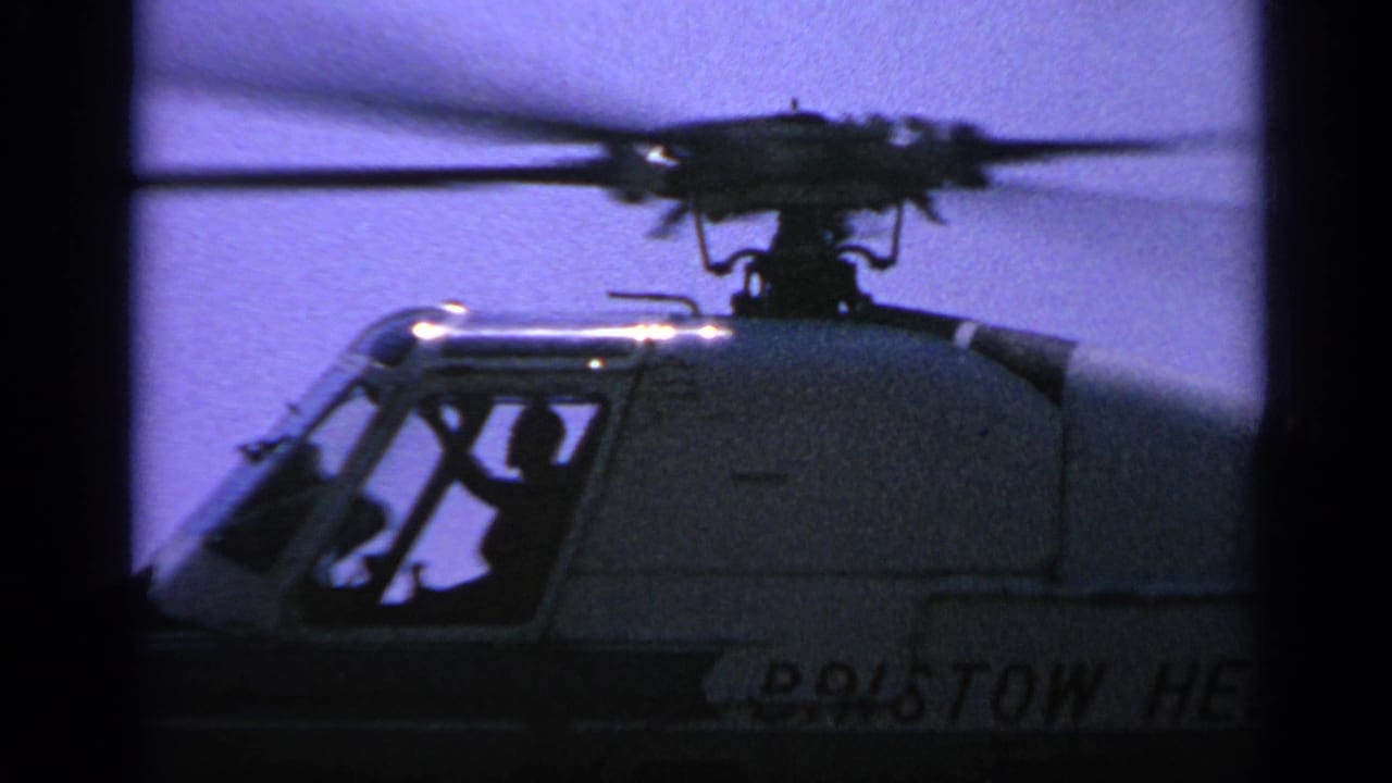 Close view of a helicopter cockpit and spinning rotor with a pilot silhouette inside.