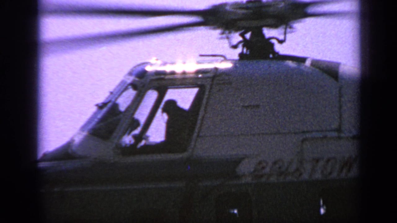 Close view of a Bristol helicopter cockpit with silhouetted crew and spinning rotor above.