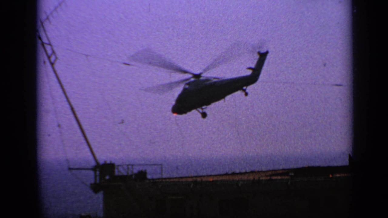 Helicopter silhouette lifting above a ship deck with mast and ocean horizon.