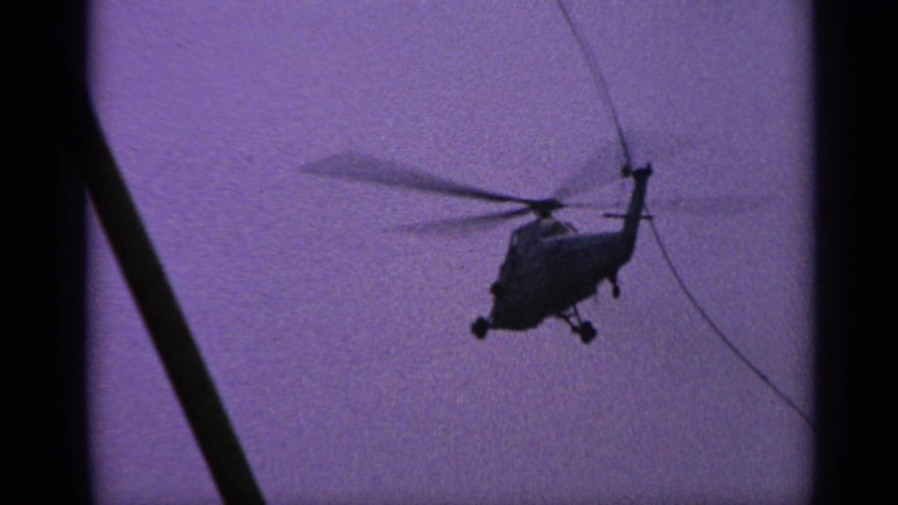 Helicopter silhouette flying against a purple sky beside dark window or pole shapes.