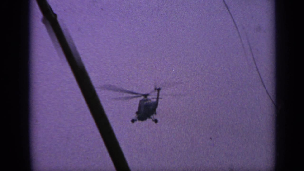 Silhouetted helicopter in open purple sky with a dark diagonal pole at left.