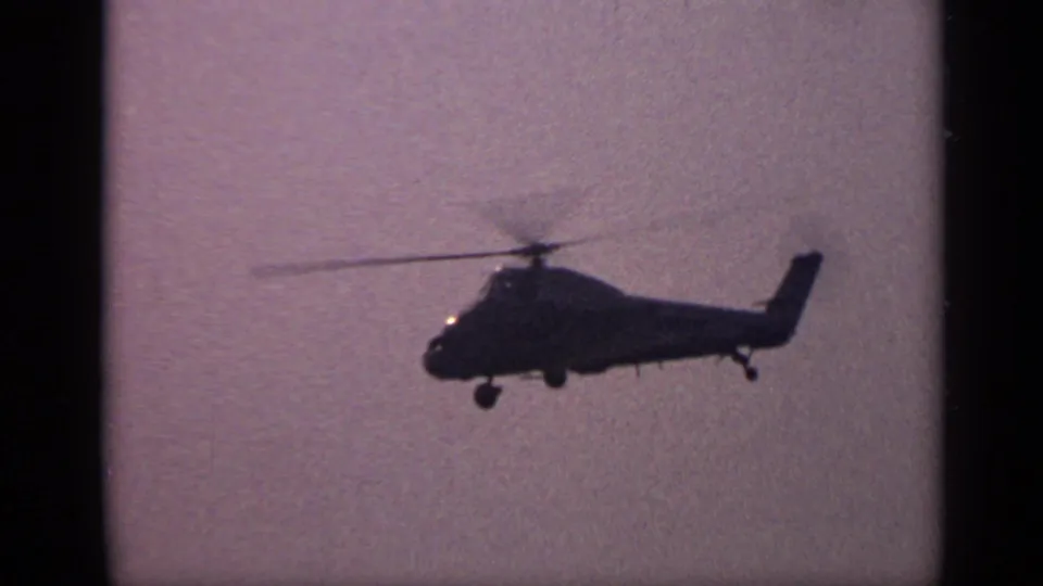 A 1970 United Kingdom 8mm still showing the helicopter lower in frame, with landing gear visible beneath the silhouetted fuselage.