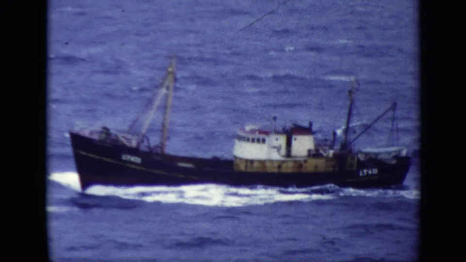 1970 United Kingdom Super 8 frame of a fishing trawler moving over choppy blue sea with hull markings visible.