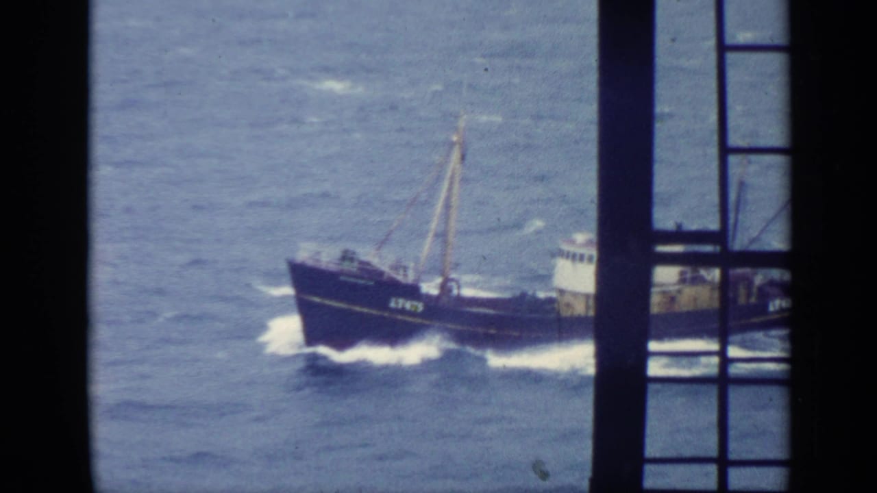 Fishing trawler partly seen through dark window bars at sea.