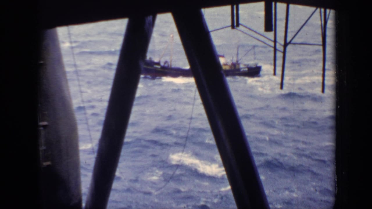 Small boat on choppy open water seen through dark beams.