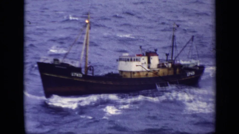 The weathered British fishing trawler marked LT475 cuts through waves in a grainy 8mm home-movie frame.
