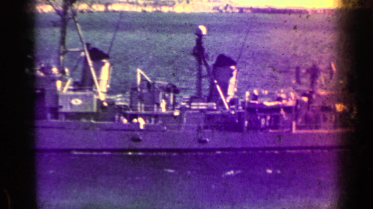 Distant naval ship on calm water with dark film gate edges and color shift.