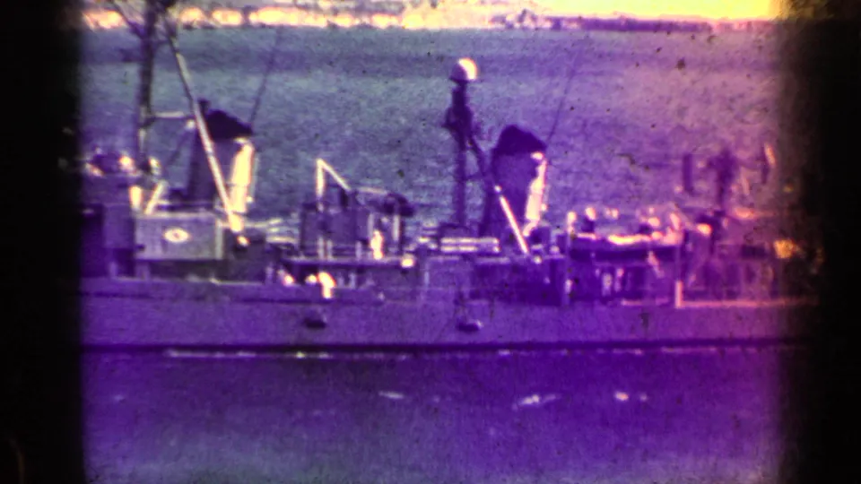 1962 Cuba 8mm frame showing a distant naval ship crossing calm water, with deck structures and heavy color fading visible.