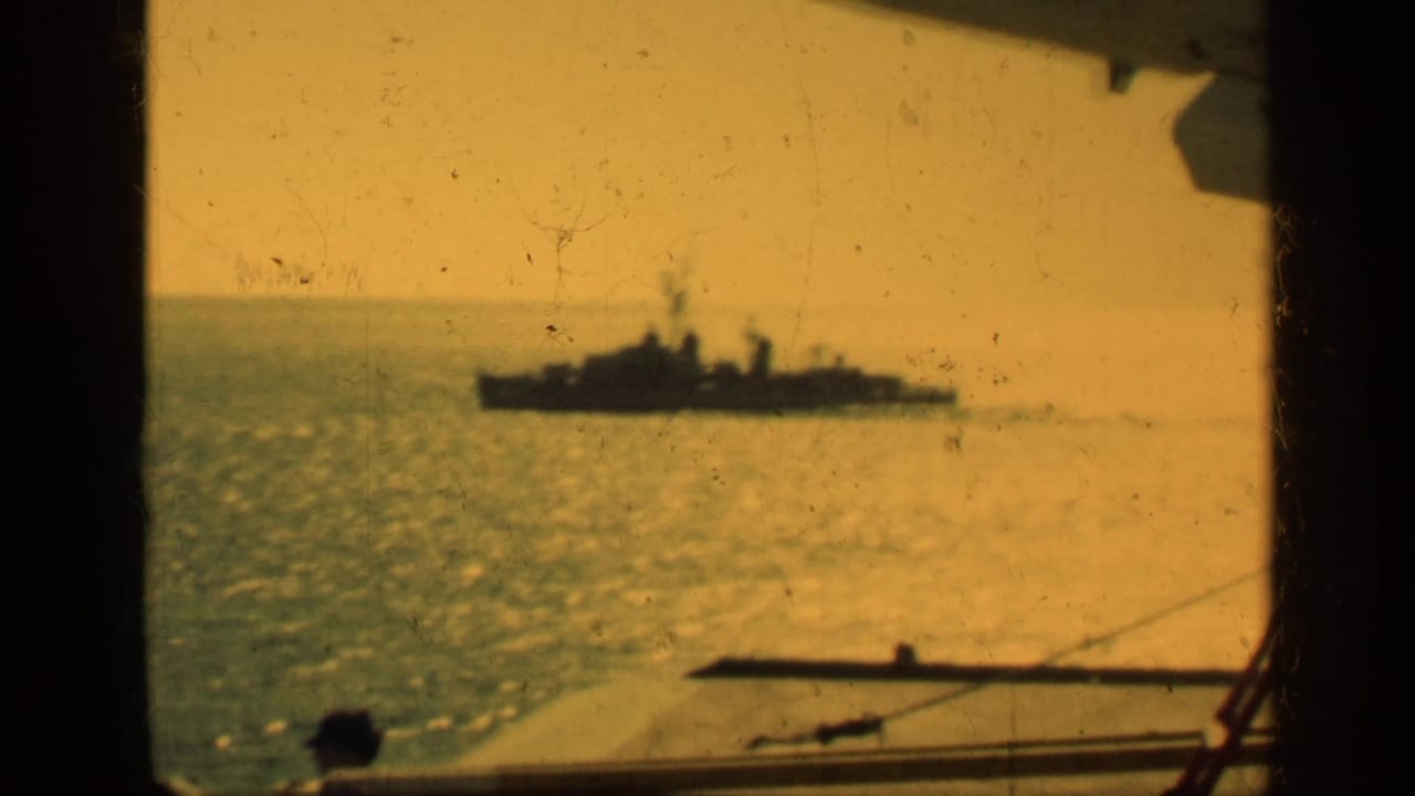 1962 Cuba 8mm frame showing a distant ship on open water, seen through a dark window frame with warm yellow tint and film wear.