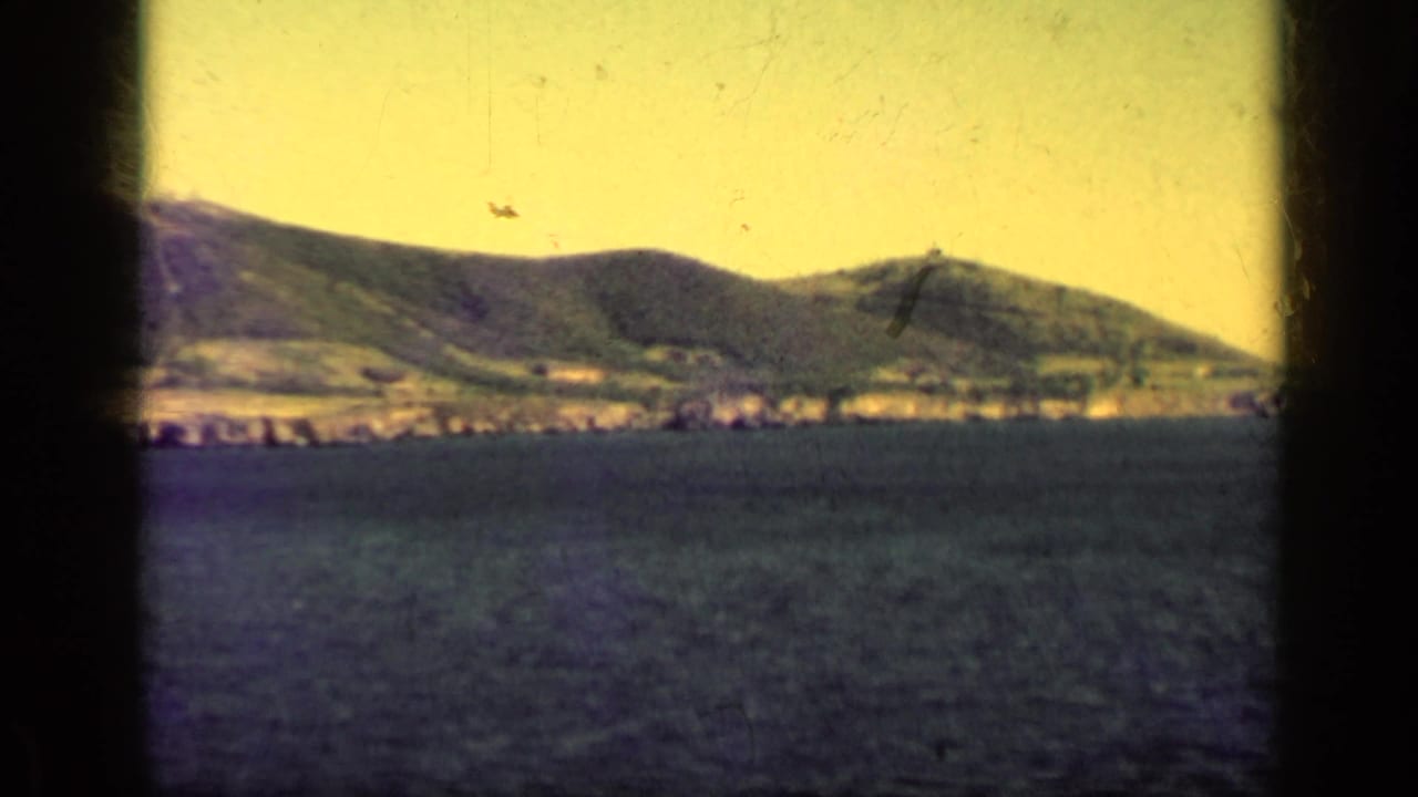 Distant mountain ridge and shoreline across water with dark frame edges.