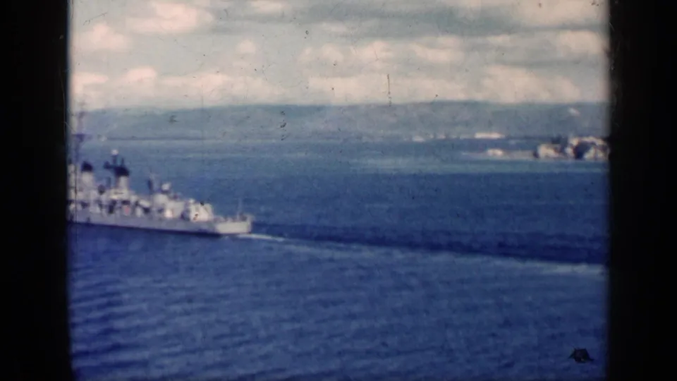 1962 Cuba 8mm frame showing a large naval-looking ship crossing blue water with wake before a distant coast.