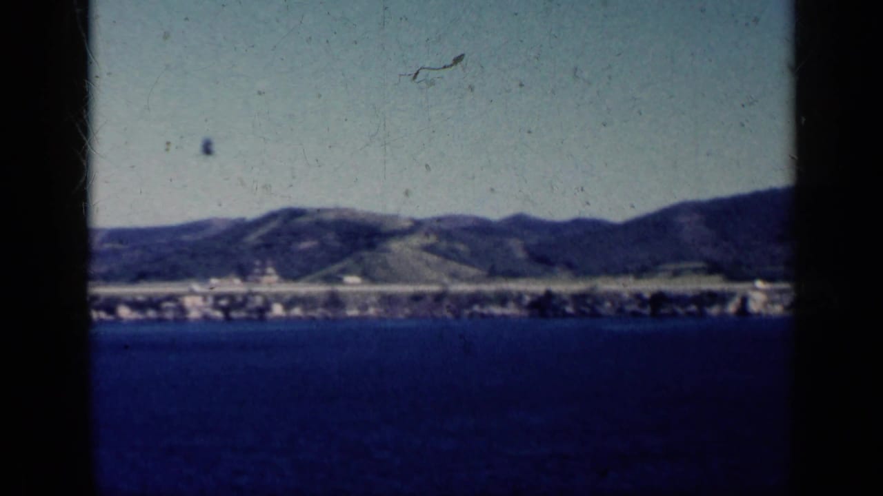 Blue water with a distant Cuban shoreline and low hills under a bright sky.