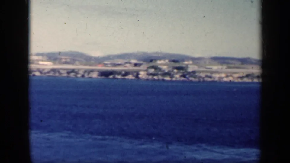 1962 Cuba 8mm frame showing blue water, distant settlement, low hills, and visible home-movie frame edges.