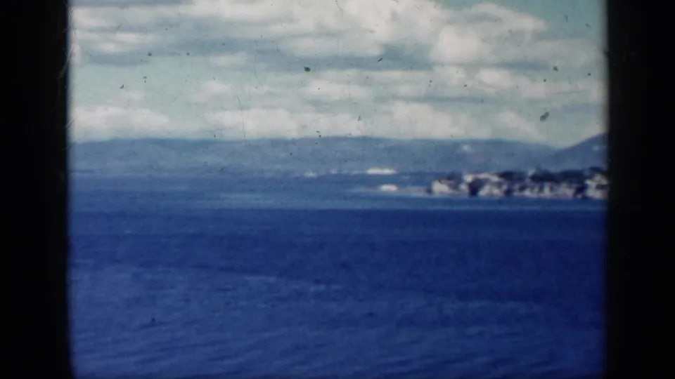 1962 Cuba home-movie frame showing open blue water, cloudy sky, and distant shoreline or mountains across the horizon.