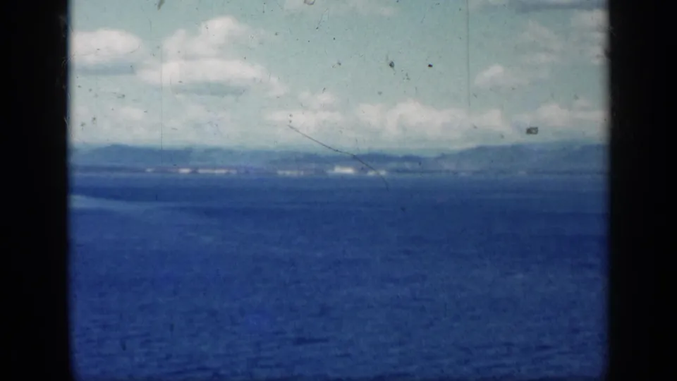 1962 Cuba 8mm frame with open water in the foreground and a faint distant shoreline under bright clouds.