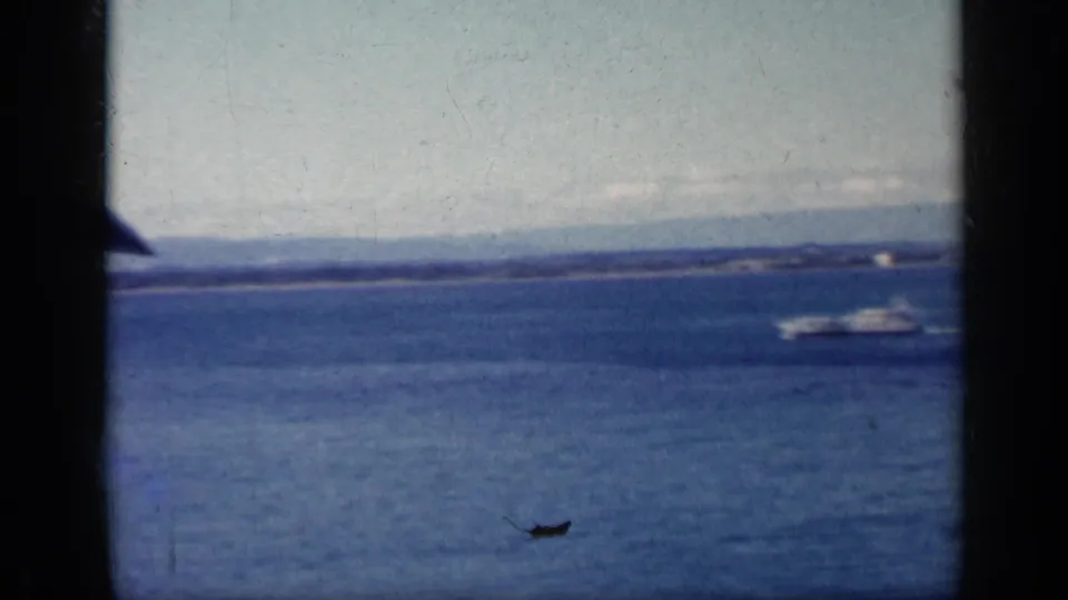1962 Cuba home-movie view of a small boat on coastal water, with a low horizon and aircraft window framing in view.