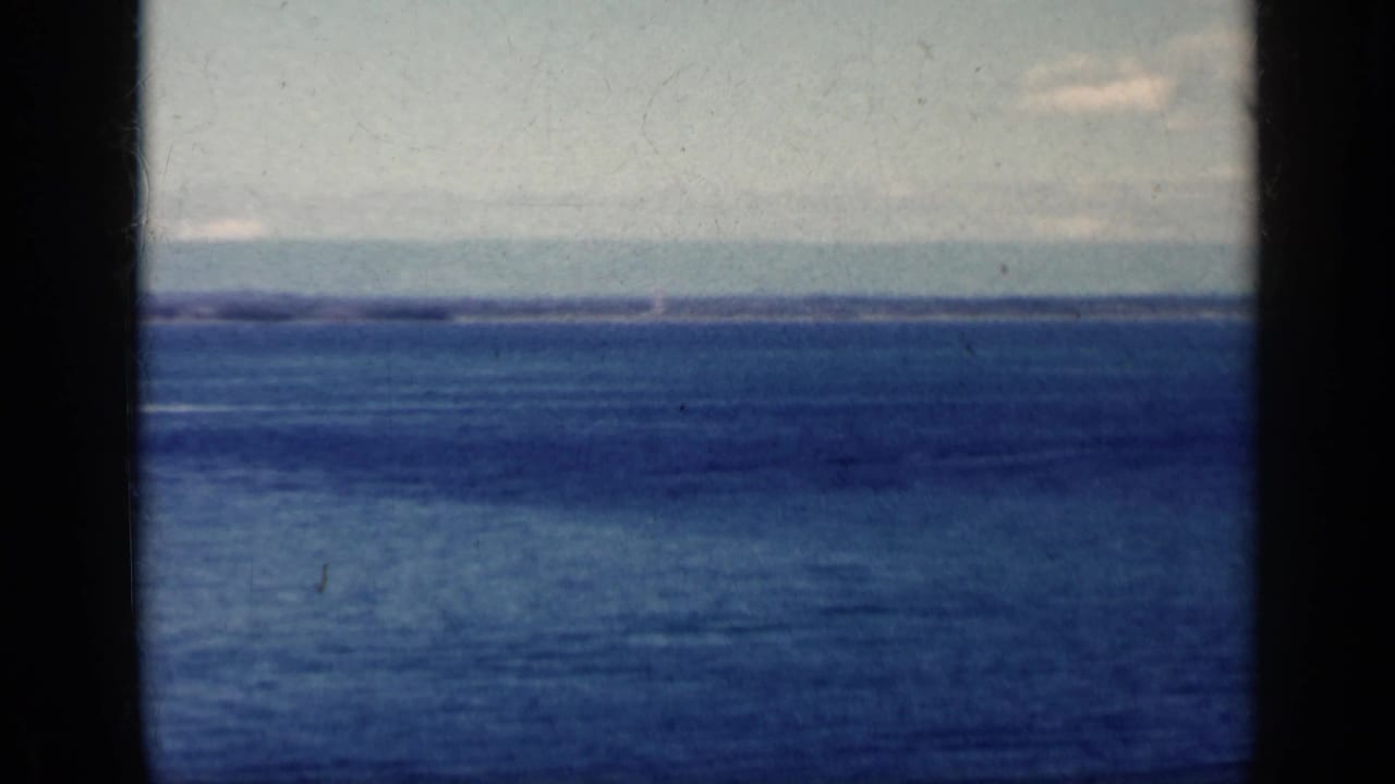 Distant blue sea and cloudy sky with a small aircraft near the right horizon.