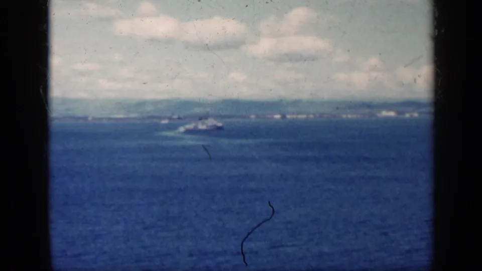 1962 Cuba 8mm frame with a small boat traveling across open water, a low shore visible in the background.