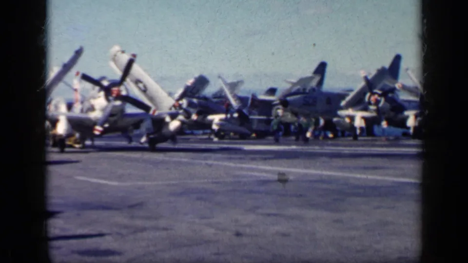 Cuba-associated 1962 8mm frame showing parked propeller naval aircraft with folded wings on a carrier flight deck.