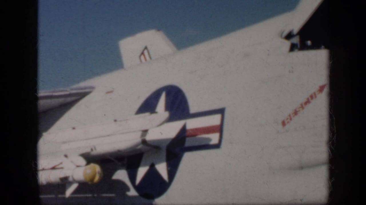 1962 Cuba-labeled 8mm frame showing a white U.S.-marked military aircraft with star-and-bar insignia and a yellow-nosed underwing object.