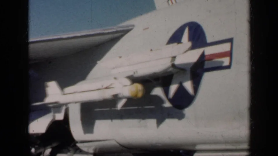 1962 Cuba-labeled frame with the aircraft side filling the view, showing the star-and-bar emblem, lower fuselage, and yellow-nosed ordnance.