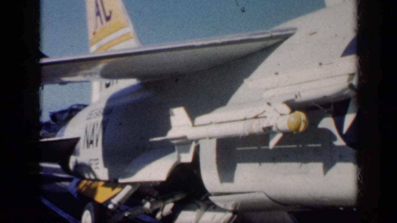Close view of a U.S. Navy jet fuselage with underwing rocket and tail markings.