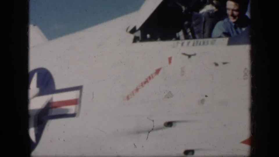 1962 Cuba-supported frame showing the Navy jet cockpit area, with visible personnel faces above fuselage markings and the U.S. roundel below.