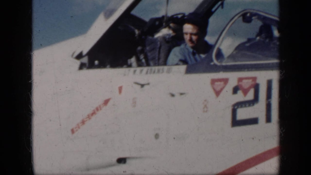 In Cuba in 1962 per metadata, a man in a blue shirt sits in an open cockpit on a white military jet marked 210.