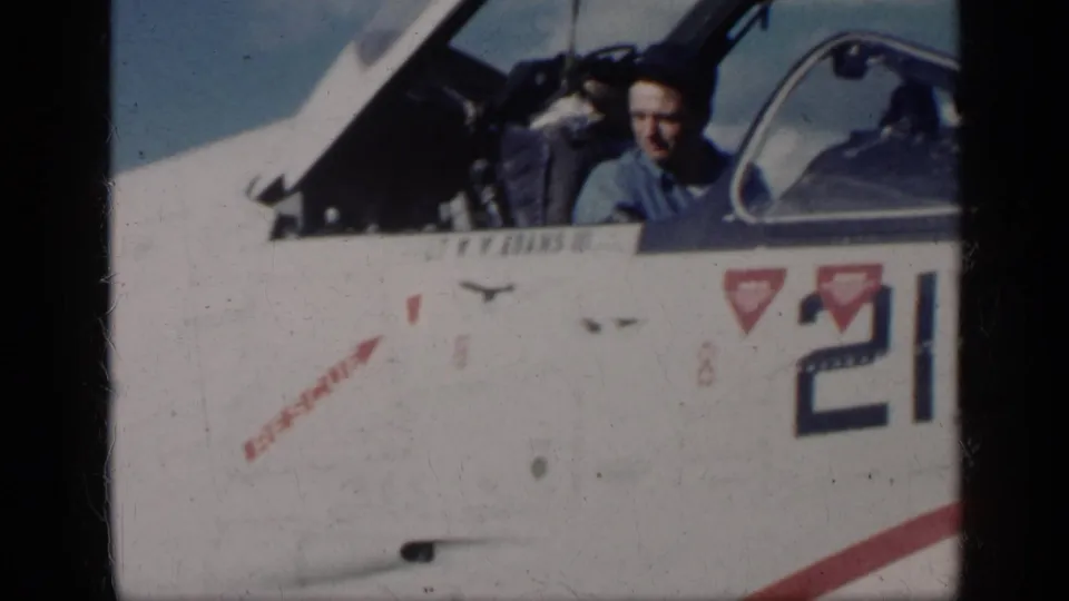 In Cuba in 1962 per metadata, a man in a blue shirt sits in an open cockpit on a white military jet marked 210.