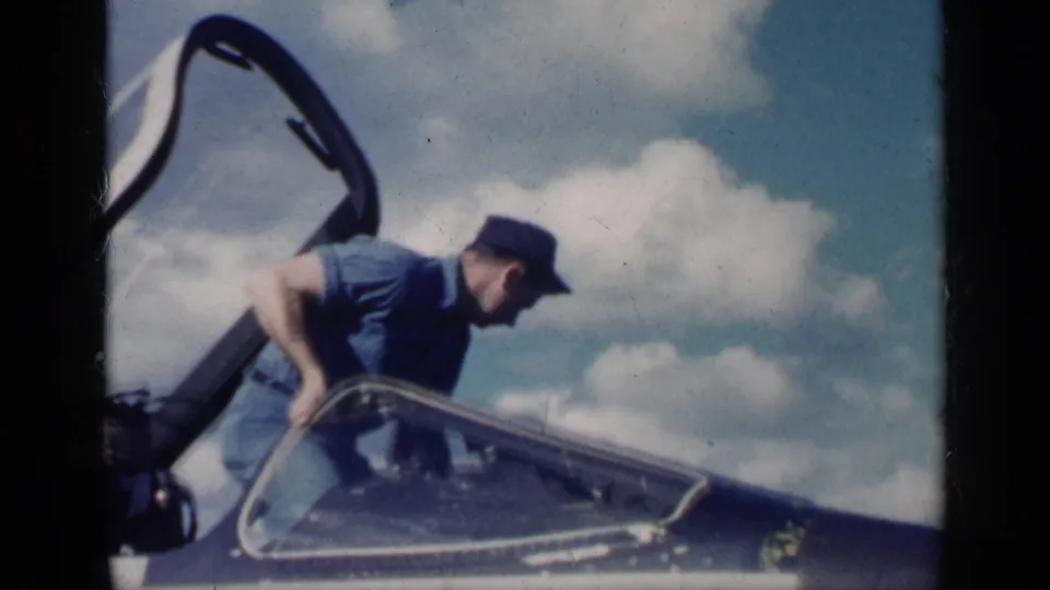 At the end of the clip, the man leans over the open cockpit as he exits the white jet, with clouds visible behind him.