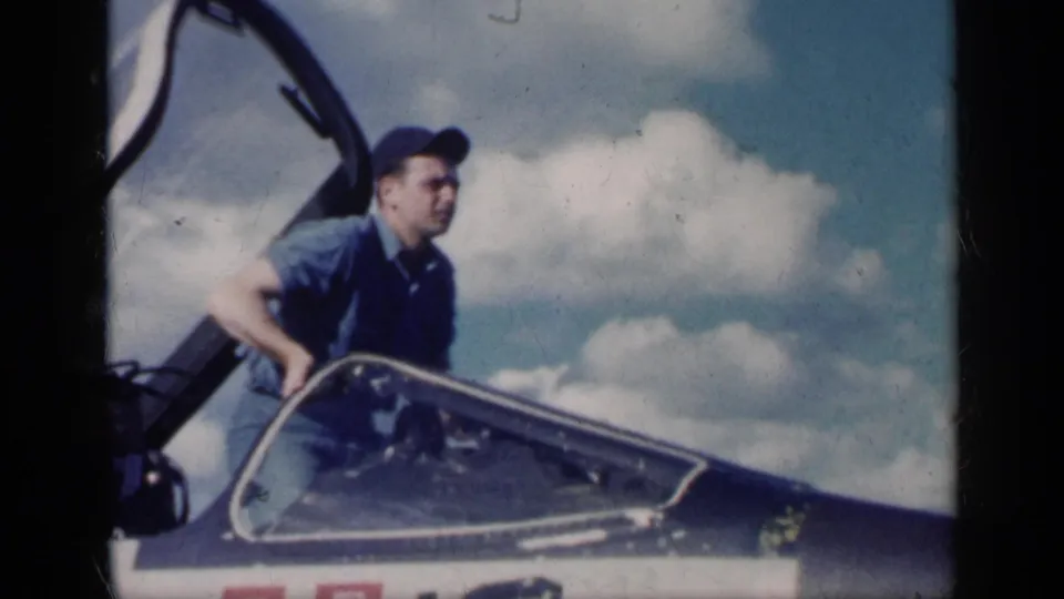 In Cuba 1962 footage, a man in a blue shirt and cap appears to climb out of an open aircraft cockpit beneath a bright cloud bank.